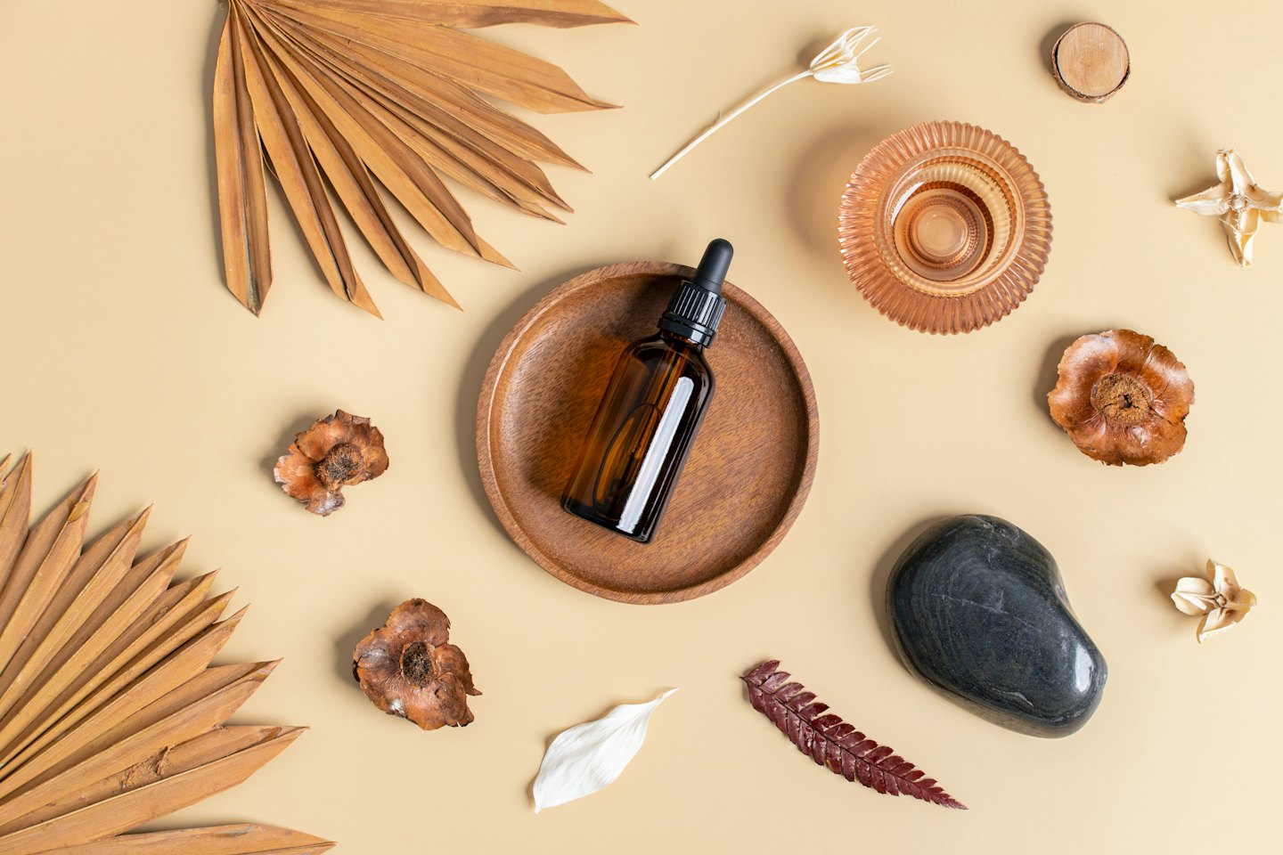 Brown glass dropper bottle on a wooden tray with dried botanicals.